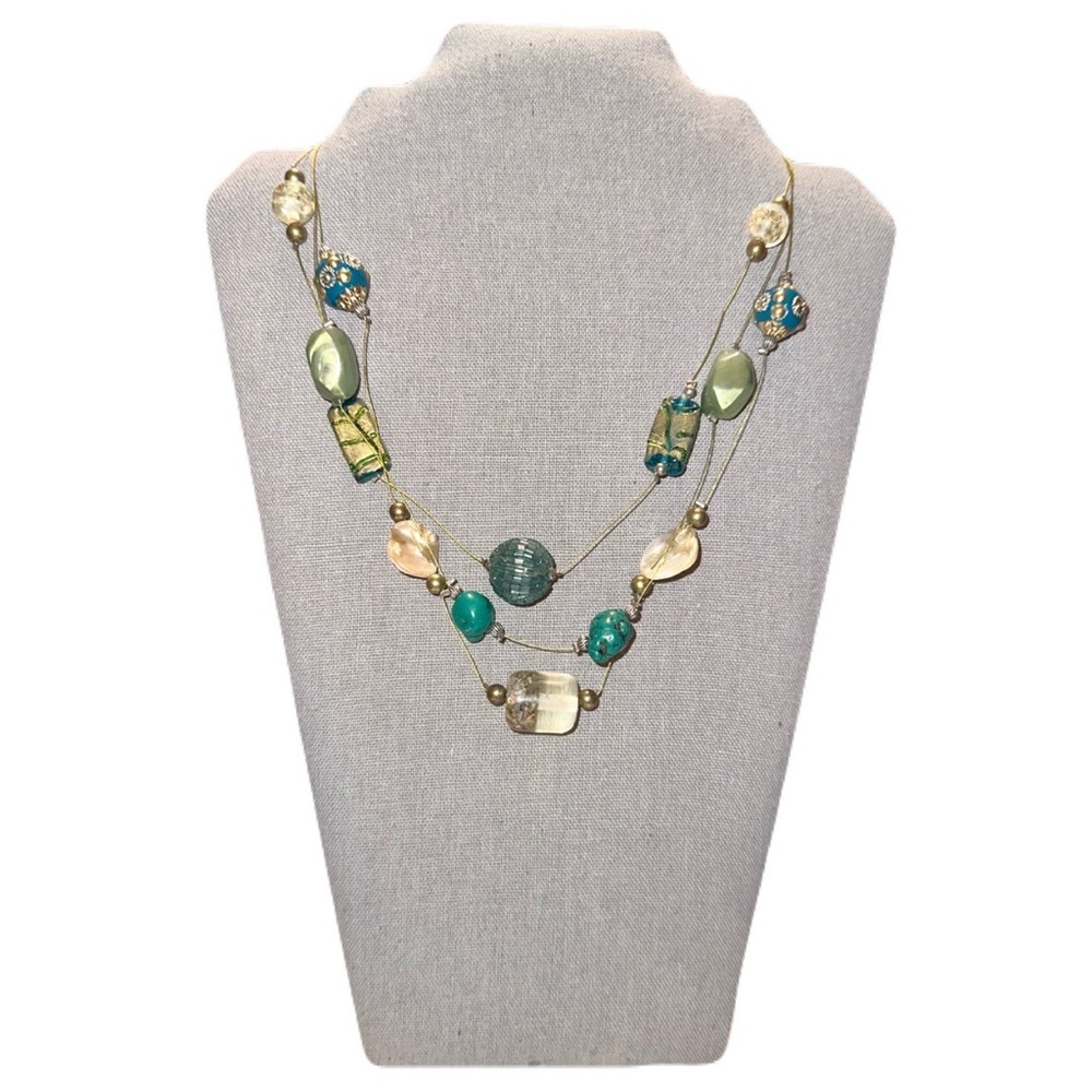 Multi-strand necklace featuring large, varied beads in shades of green, blue